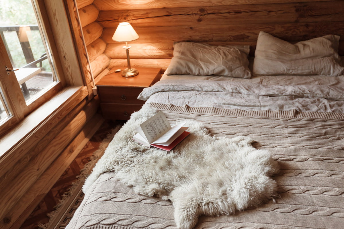 A cosy bed with soft linens in a warm wooden bedroom